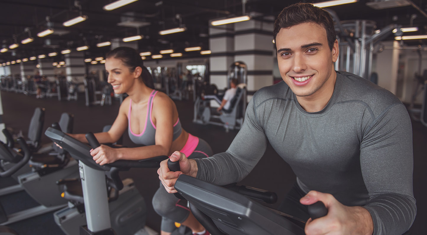 Attractive young muscular man and woman doing plank exercise while working out in gym